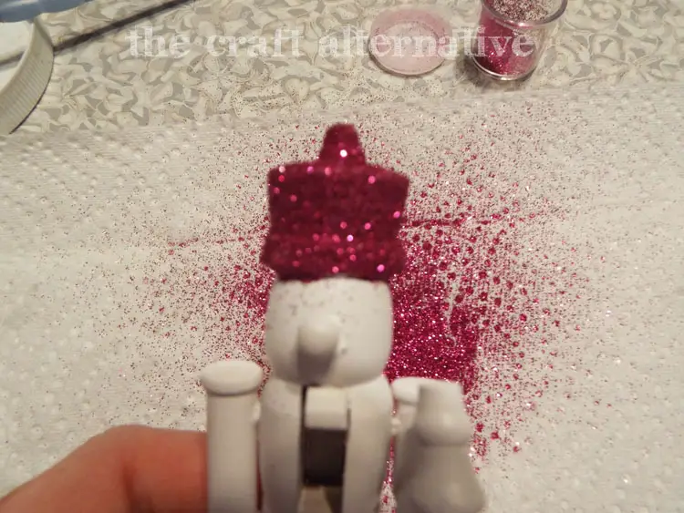 DIY Painted Nutcrackers with Glitter Hats apply glitter over the Mod Podge
